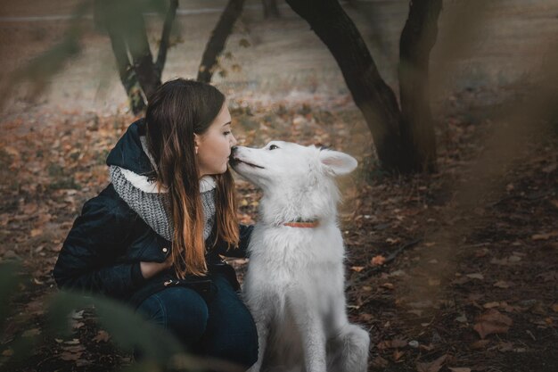 ハンサムな赤毛の髪の若い女性が、犬を抱きしめ、キスをします。犬と飼い主の愛。