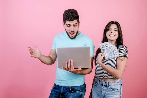 Handsome rich young couple man and woman with laptop and dollar bills 