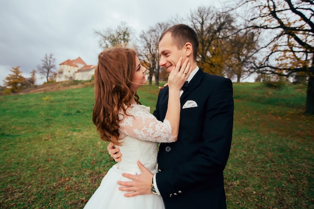Красивый романтический жених целует красивую брюнетку невесту в день своей счастливой свадьбы на территории дворца