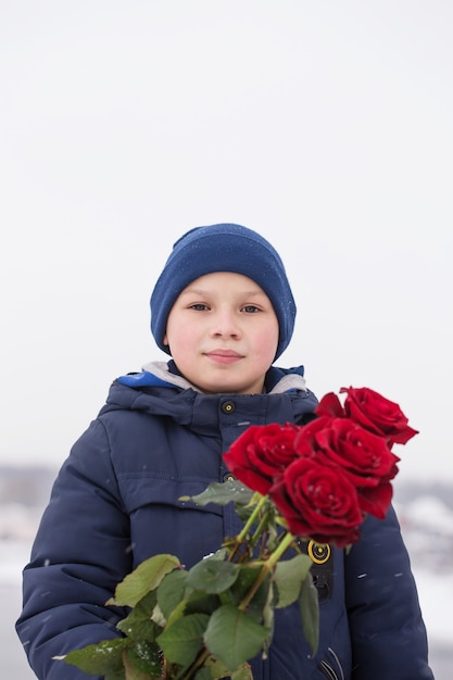 手に赤いバラの花束を持つハンサムなロマンチックな若い男