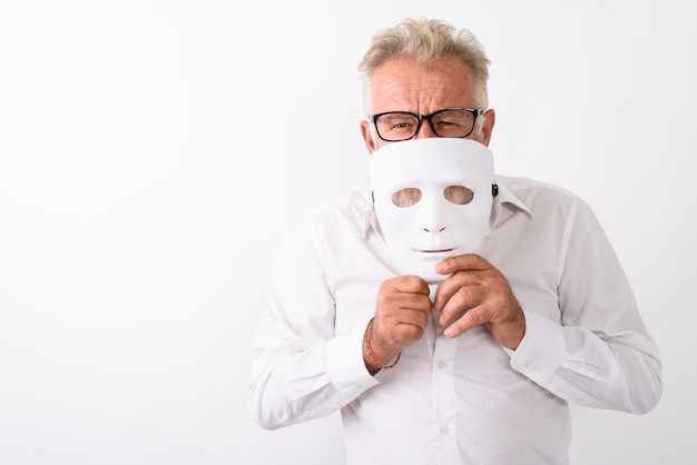 Фото Красивый старший бородатый мужчина прикрывает рот белой маской в очках на белом
