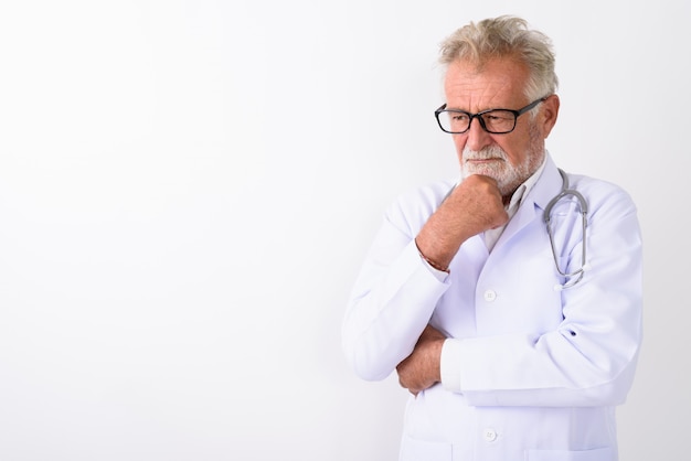 handsome senior bearded man doctor thinking while looking down on white