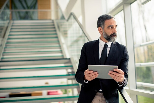 Handsome senior businessman with digital tablet in the modren office