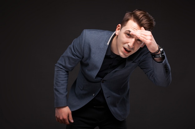 Handsome serious businessman in grey jacket, costly watch and black shirt