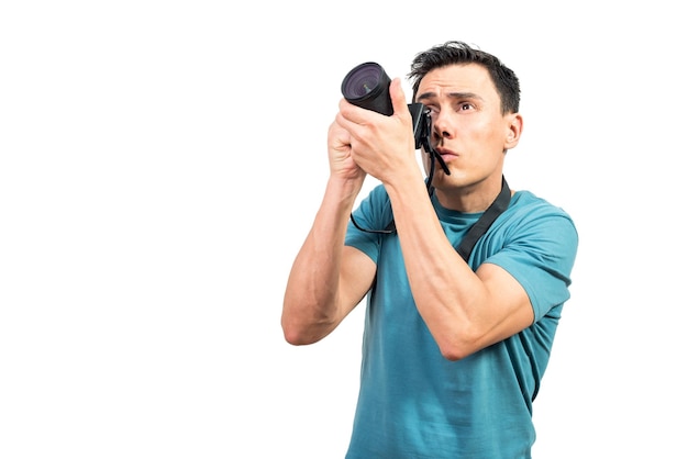 Handsome serious male photographer taking photos on professional camera while looking up on white isolated background