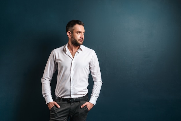 Handsome serious man standing over dark blue wall