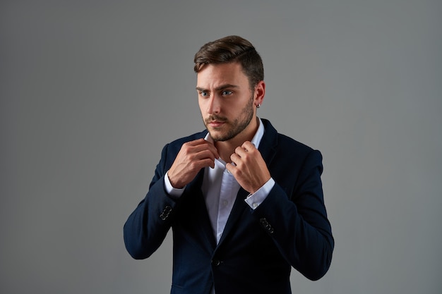 Handsome serious young businessman on gray background