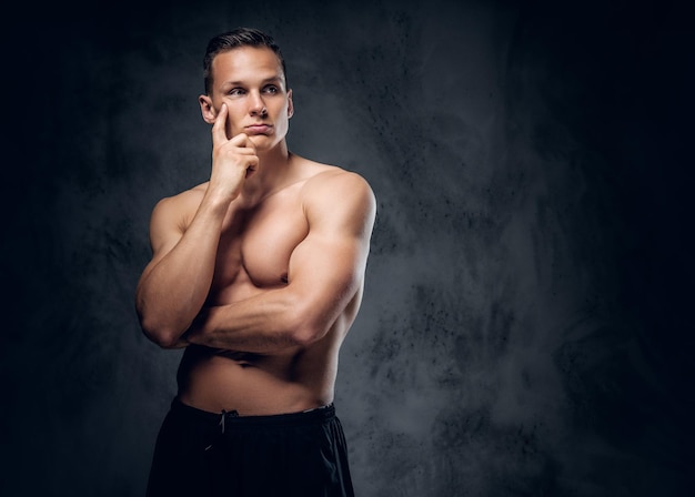 Handsome shirtless athletic male over grey vignette background.