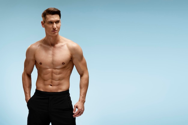 Handsome shirtless athletic young man in pants posing in front of the camera