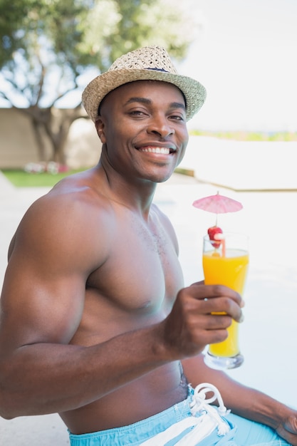 Handsome shirtless man relaxing with cocktail poolside