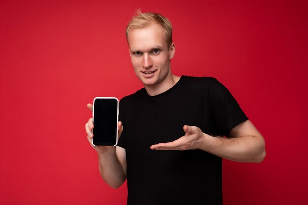 Handsome smiling blonde young male person wearing black t-shirt standing isolated