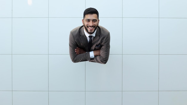 Handsome smiling business man in a suit standing with his arms crossed