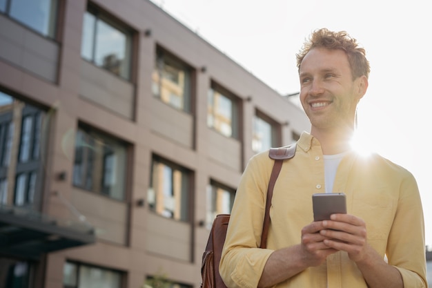 Handsome smiling business man using mobile phone shopping online on the street