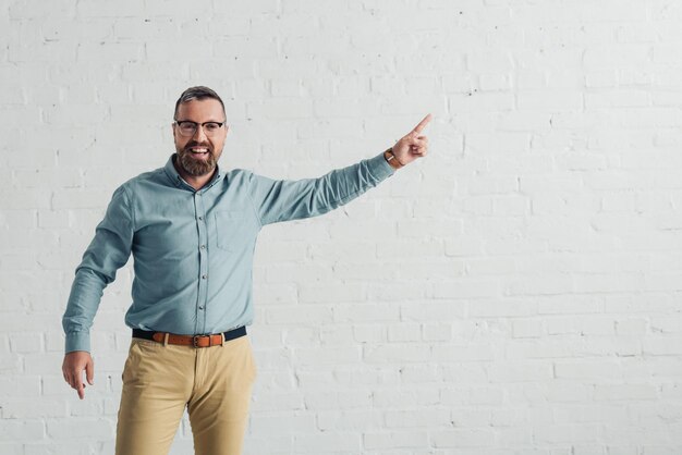 Handsome and smiling businessman in shirt pointing with finger