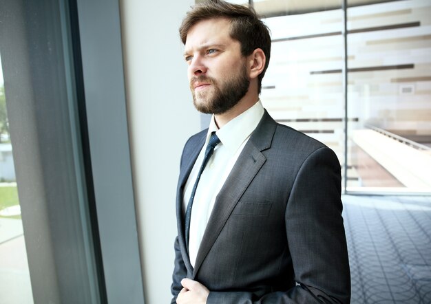 Handsome smiling confident businessman portrait in office