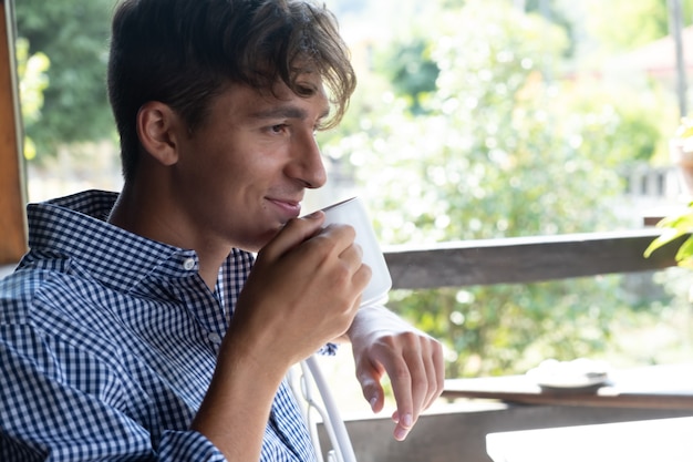 Handsome smiling guy with white cup of tea