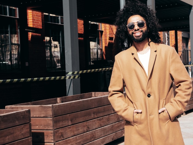 handsome smiling hipster model arabian man dressed in brown coat outdoors in street