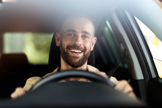 車を運転するハンサムな笑顔のラテン男。交通機関、カーシェアリングのコンセプト