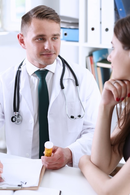 Handsome smiling male doctor hold in arms jar of pills