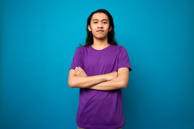 Handsome smiling  male teenager with long hair on blue background