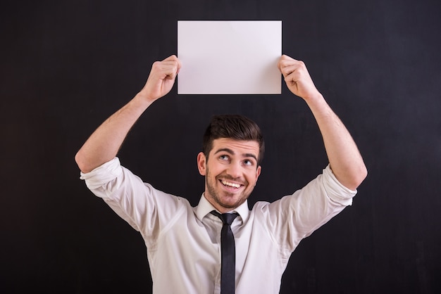 Handsome, smiling man is holding white blank.