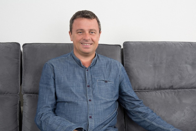 Photo handsome and smiling man sitting in couch