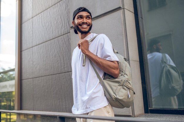 Красивый улыбающийся мужчина с рюкзаком на городской улице