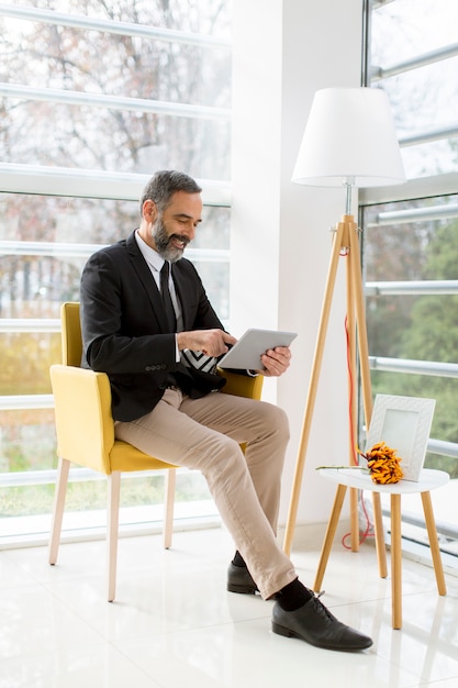 Handsome smiling mature businessman with tablet in the office working