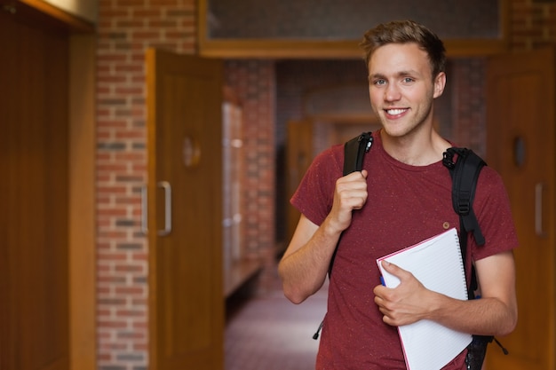 Handsome smiling student standing in hallway