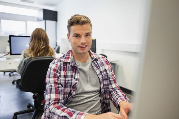 Foto studente sorridente bello che lavora al computer