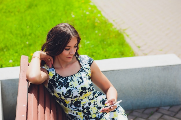 通りを歩いて携帯電話でハンサムな笑顔の女性