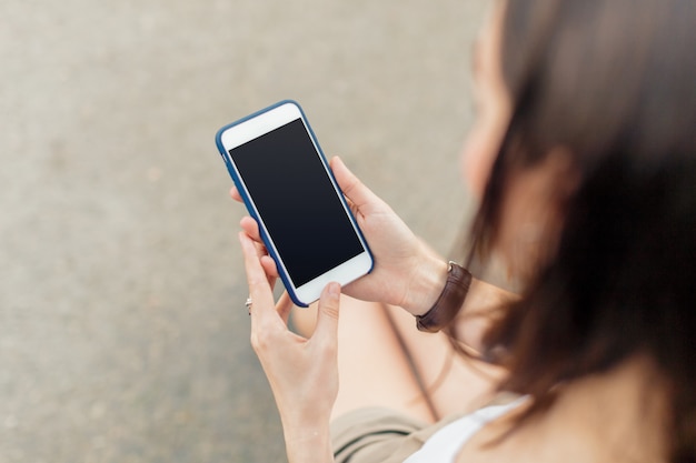 Handsome smiling woman with mobile phone walking on the street