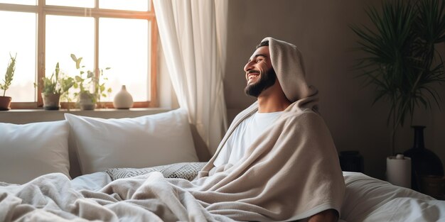 素敵な笑顔の若い男が 居心地の良い寝室でリラックスし 家の快適さを楽しんでいます