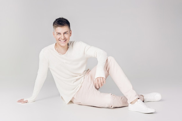 Photo handsome smiling young man in a white sweater looks at the camera