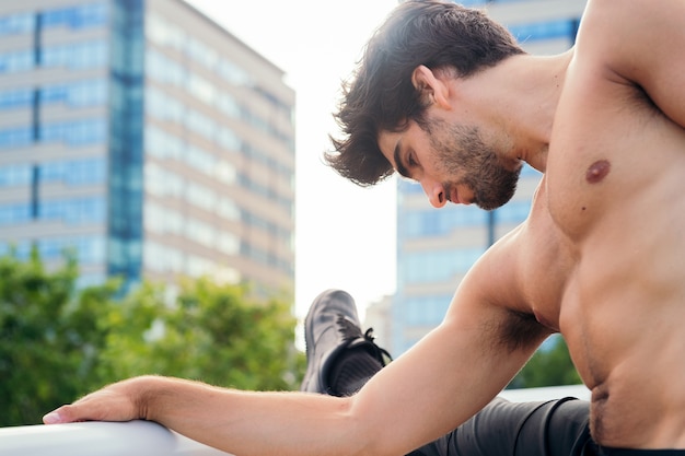 Handsome sportsman stretching his leg muscles