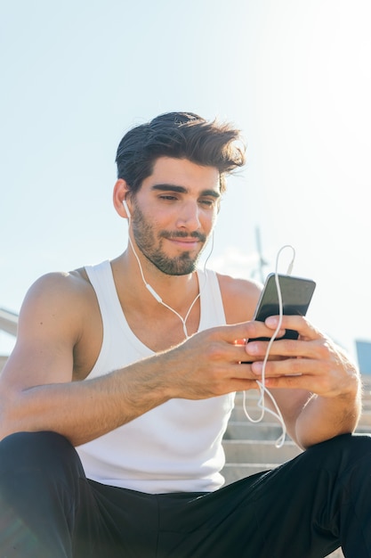 Handsome sportsman with earphones listening music