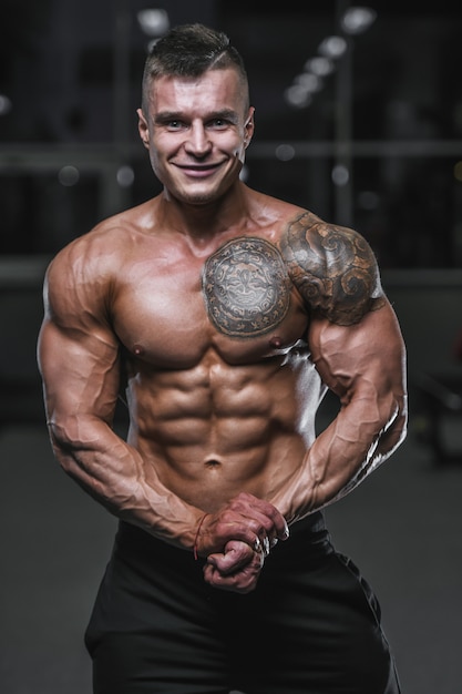 Handsome strong bodybuilder athletic men pumping up muscles with dumbbells