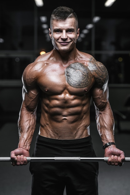 Handsome strong bodybuilder athletic men pumping up muscles with dumbbells