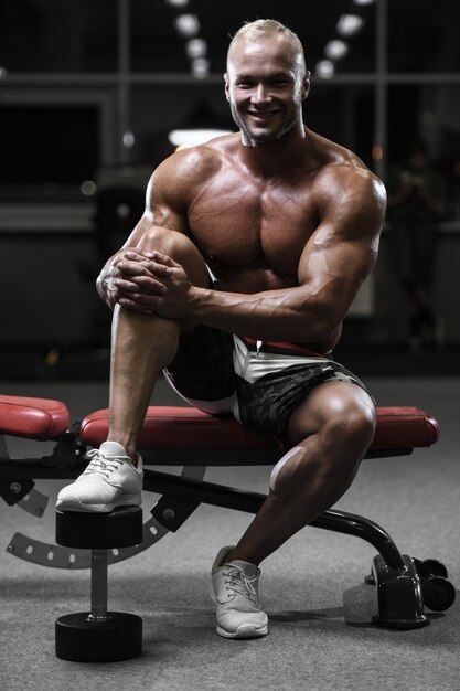 Handsome strong bodybuilder athletic men pumping up muscles with dumbbells