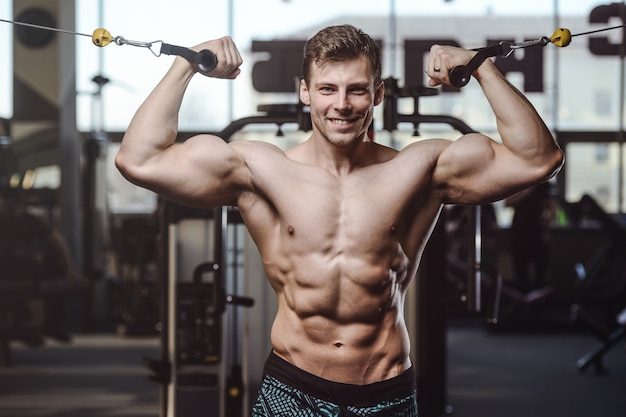 Handsome strong bodybuilder athletic men pumping up muscles with dumbbells