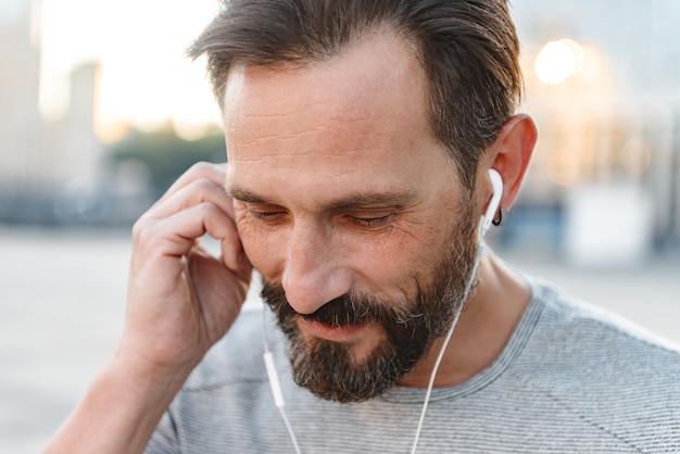 handsome strong mature sportsman listening music with earphones.