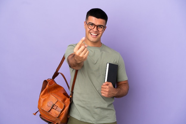Handsome student man over isolated background doing coming gesture