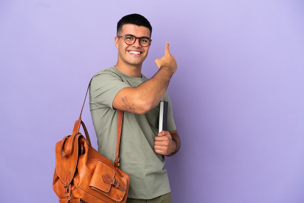 Handsome student man over isolated wall pointing back