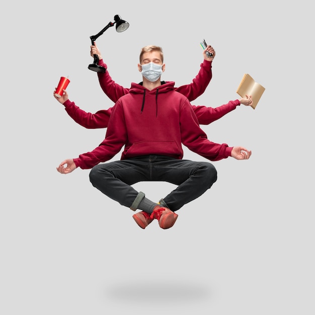 Handsome student, multi-armed man levitating isolated on grey studio background with equipment. Concept of professional occupation, work, job, education, development. Multi-task like Shiva.