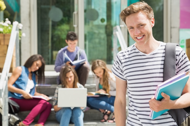 Studente bello che sorride alla macchina fotografica fuori