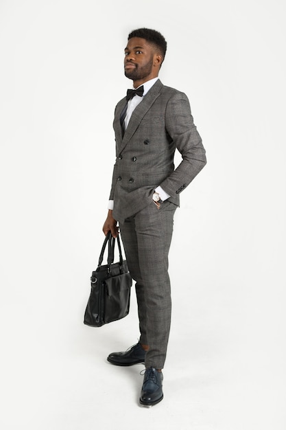 красивый стильный африканский мужчина в костюме с сумкой в руке на белом фоне