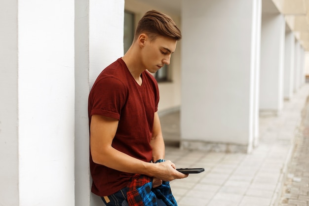 Handsome stylish guy walks in the city and uses a mobile phone