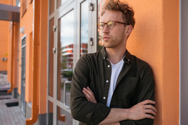 Uomo alla moda bello che indossa abbigliamento casual che distoglie lo sguardo in piedi sulla strada