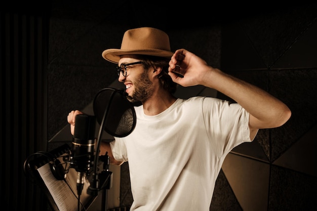 Handsome stylish musician happily dancing and singing while recording new song in modern sound studio