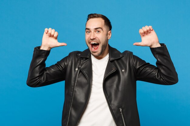 Handsome stylish young unshaven man in black leather jacket white t-shirt looking camera isolated on blue wall background studio portrait. People sincere emotions lifestyle concept. Mock up copy space